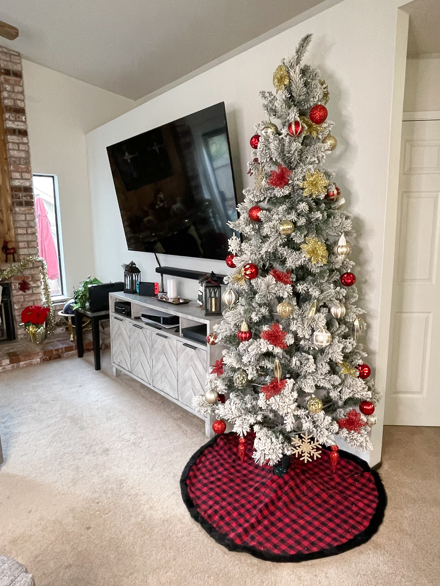 A white flocked Christmas tree decorated with red and gold ornaments